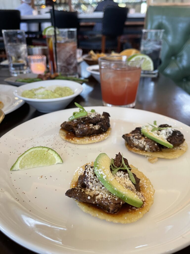 TACOS ON A PLATE with drinks in the background