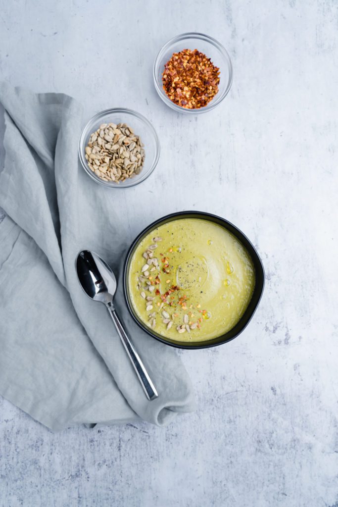 Asparagus soup on a bowl with chili flakes and sunflower seeds