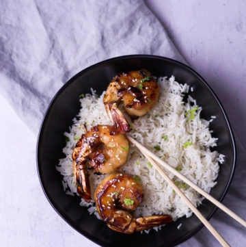 shrimp served on a bowl with rice and chopsticks