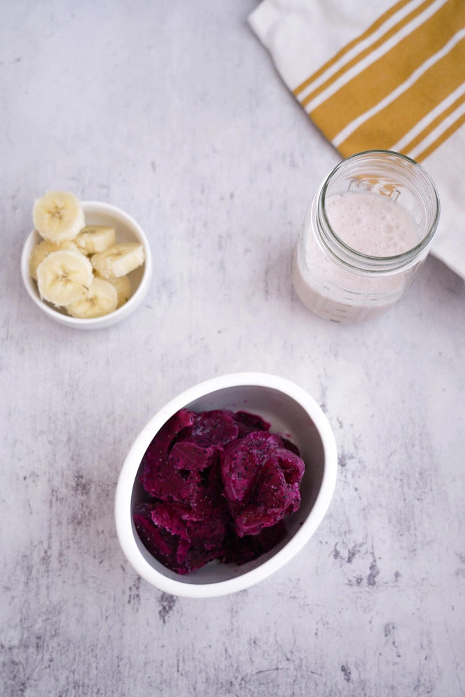 frozen dragon fruit in bowl, sliced banana, coconut milk