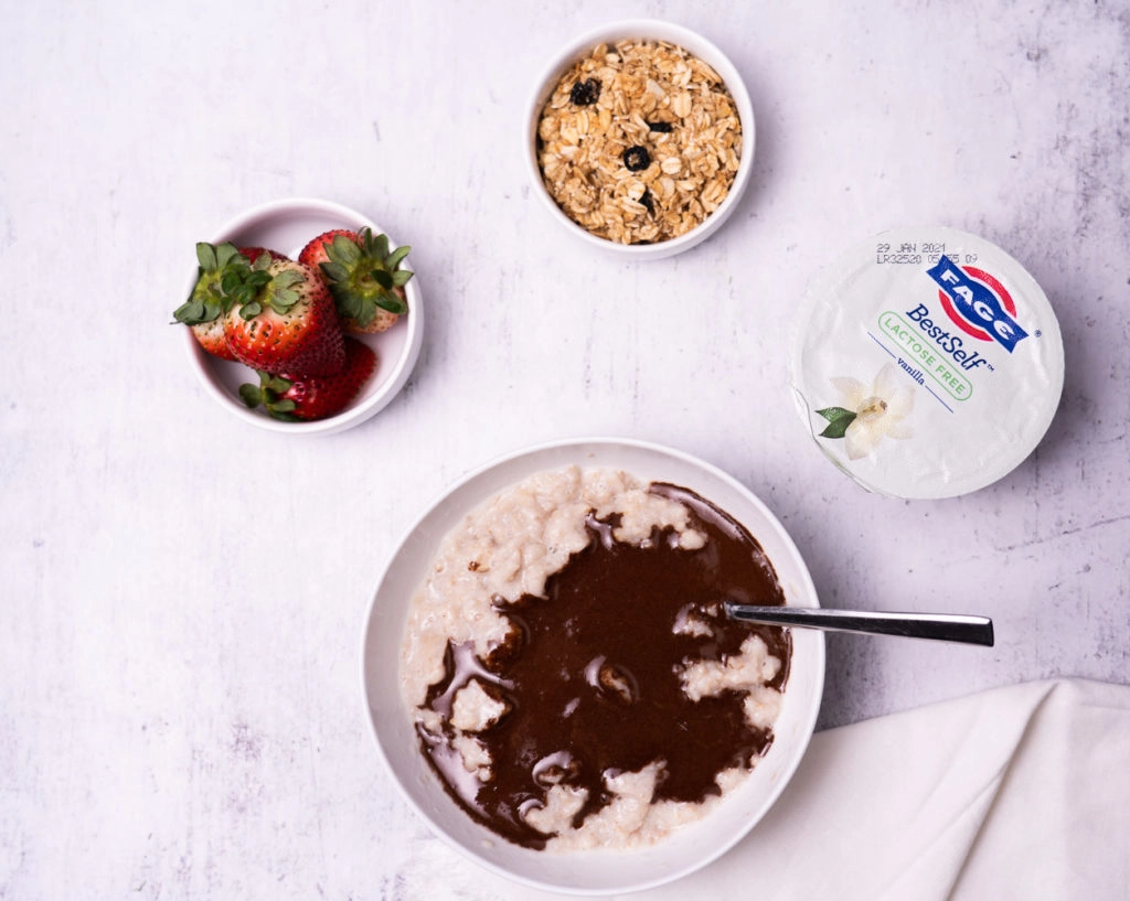 Protein oatmeal in bowl with strawberries, granola and yogurt