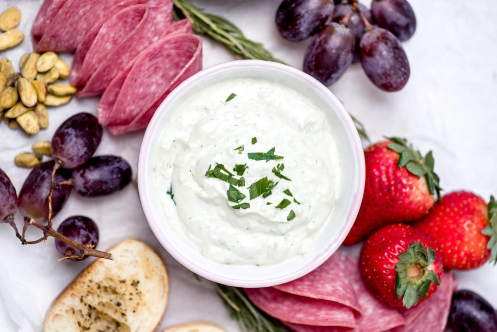 mini grazing board with cheese dip, meat, grapes, bread and nuts