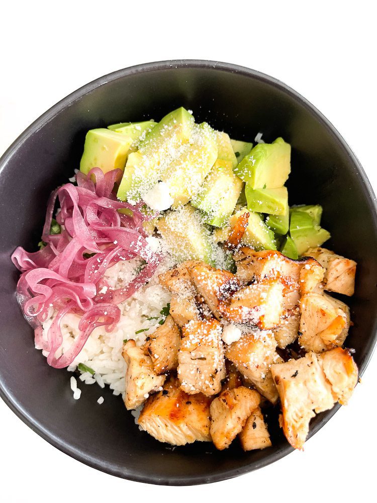 chicken, rice, avocado, pickled onion, cheese in a bowl