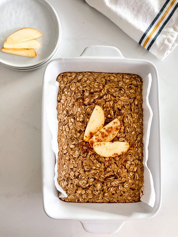 baked oatmeal on baking dish with linen and side plates. served with apple
