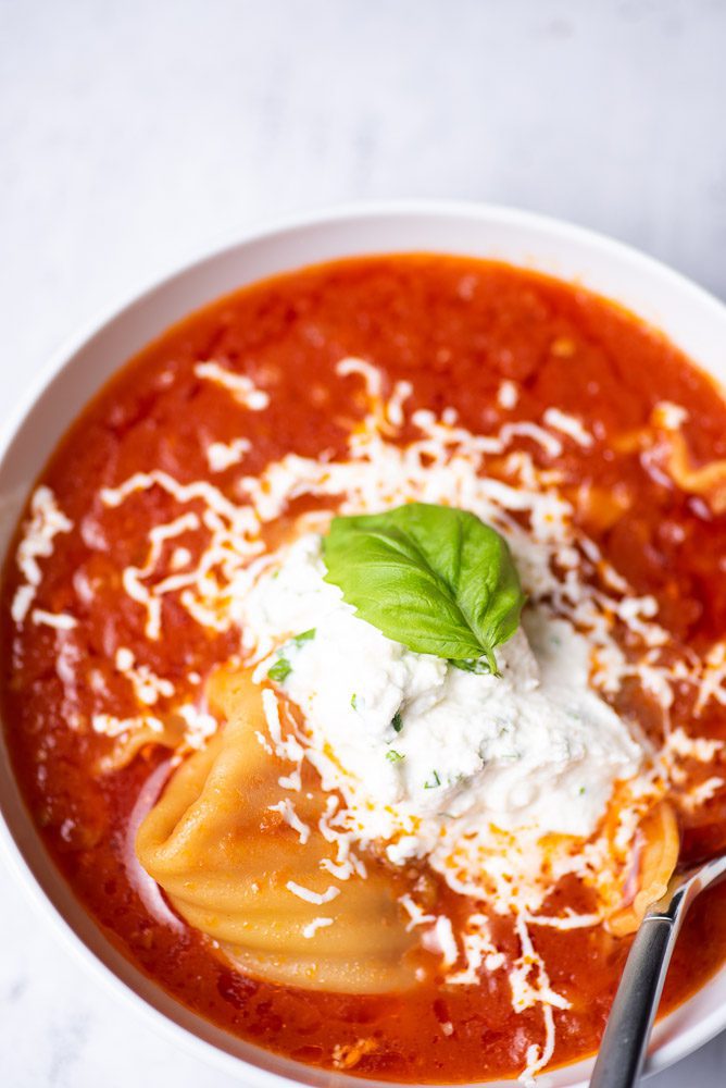 lasagna soup in a bowl with ricotta and basil
