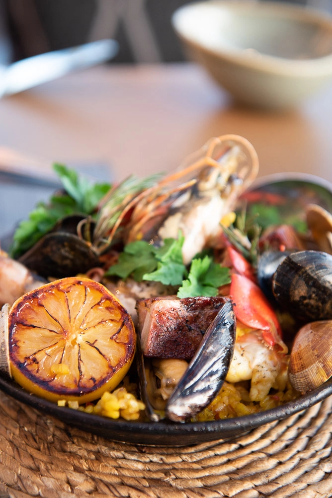 Paella with roasted lemon, pork belly, prawns on dish
