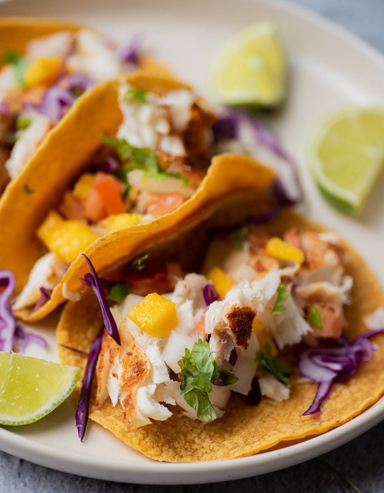 Fish tacos on plate with corn tortillas, coleslaw and mango salsa