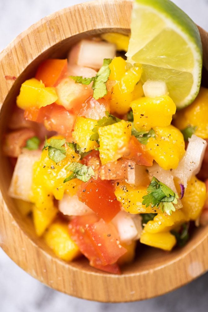 diced mango, cilantro, diced onion, tomato and lime in bowl