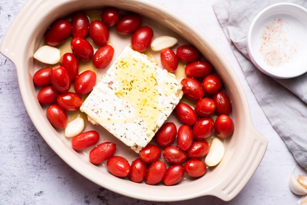 block of feta cheese with tomatoes and garlic on baking pan