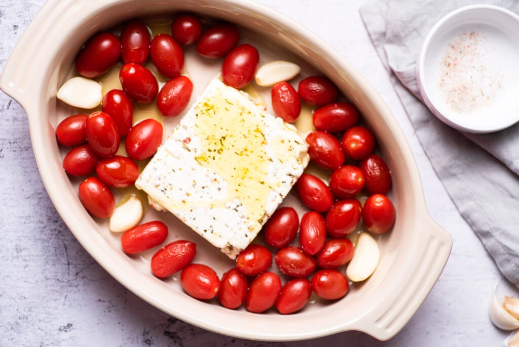 block of feta cheese with tomatoes and garlic on baking pan