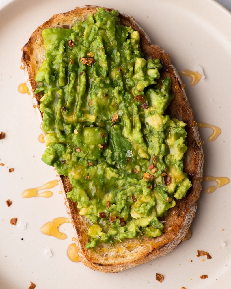 bread with avocado spread and honey topped with sea salt and chili flakes