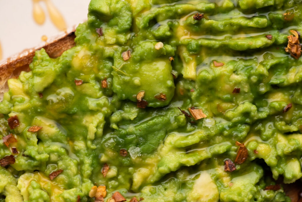 bread with avocado spread and honey topped with sea salt and chili flakes