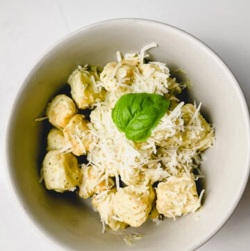 cauliflower gnocchi on a bowl with pesto creamy sauce and parmesan cheese with basil leaf