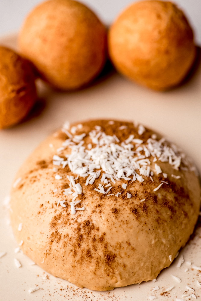 Colombian buñuelos y natilla on a plate sprinkled with coconut and cinnamon