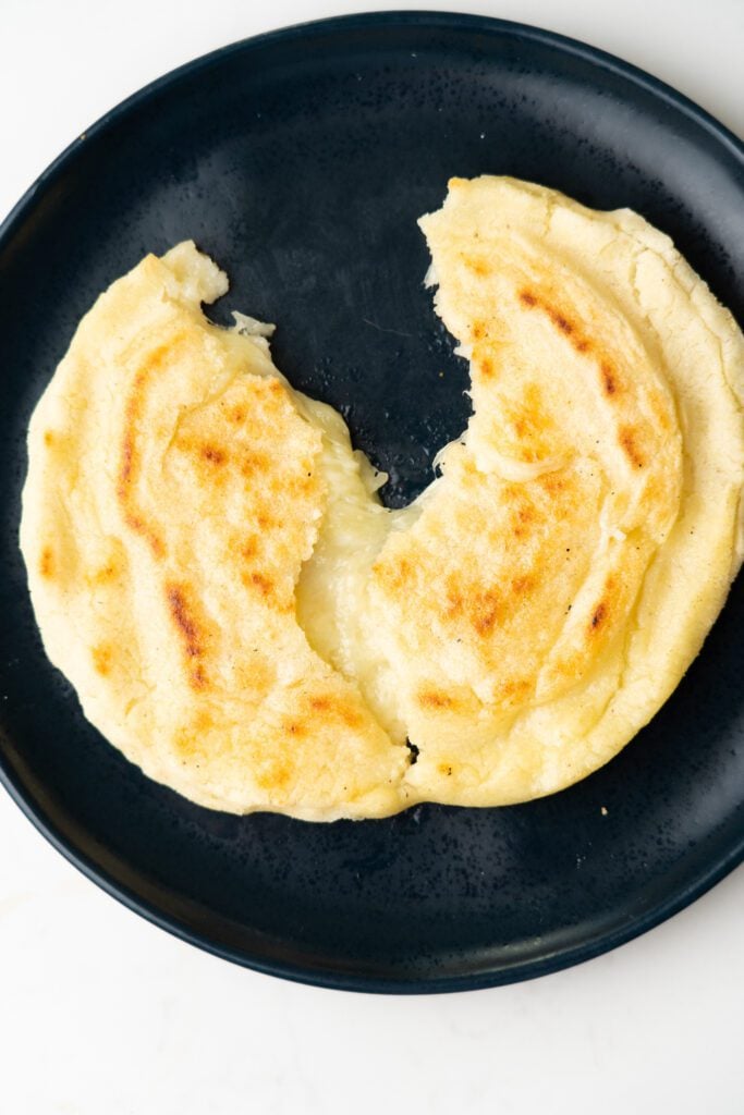 Arepas with cheese split in the middle on a plate