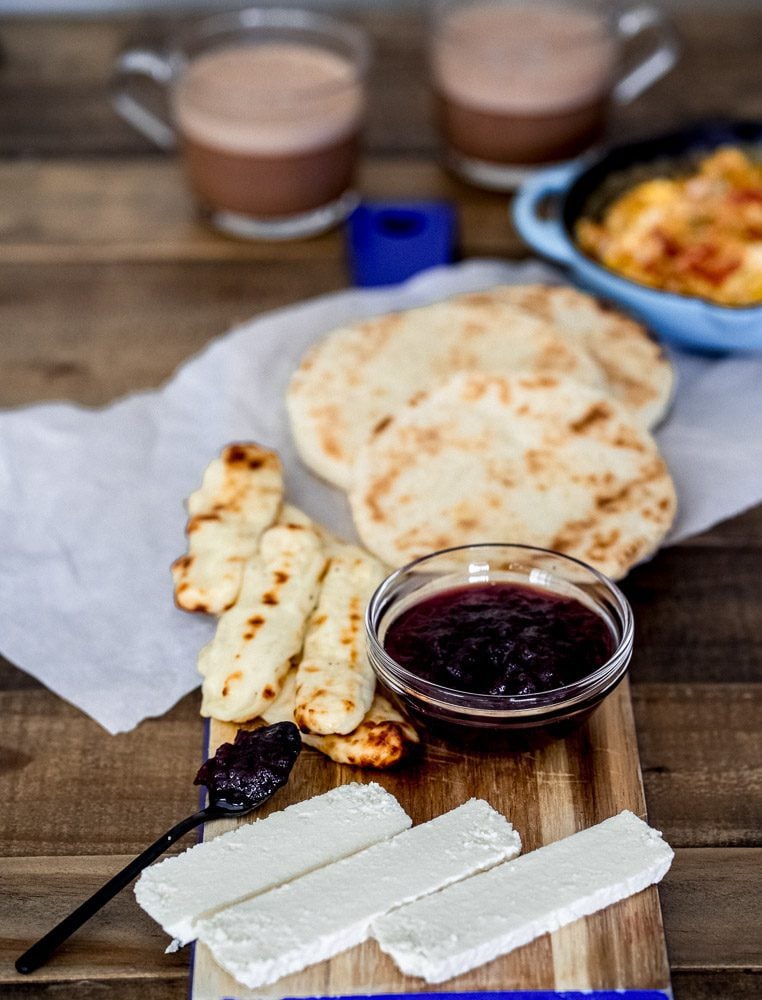Board with Colombian quesito, arepas, eggs, jam