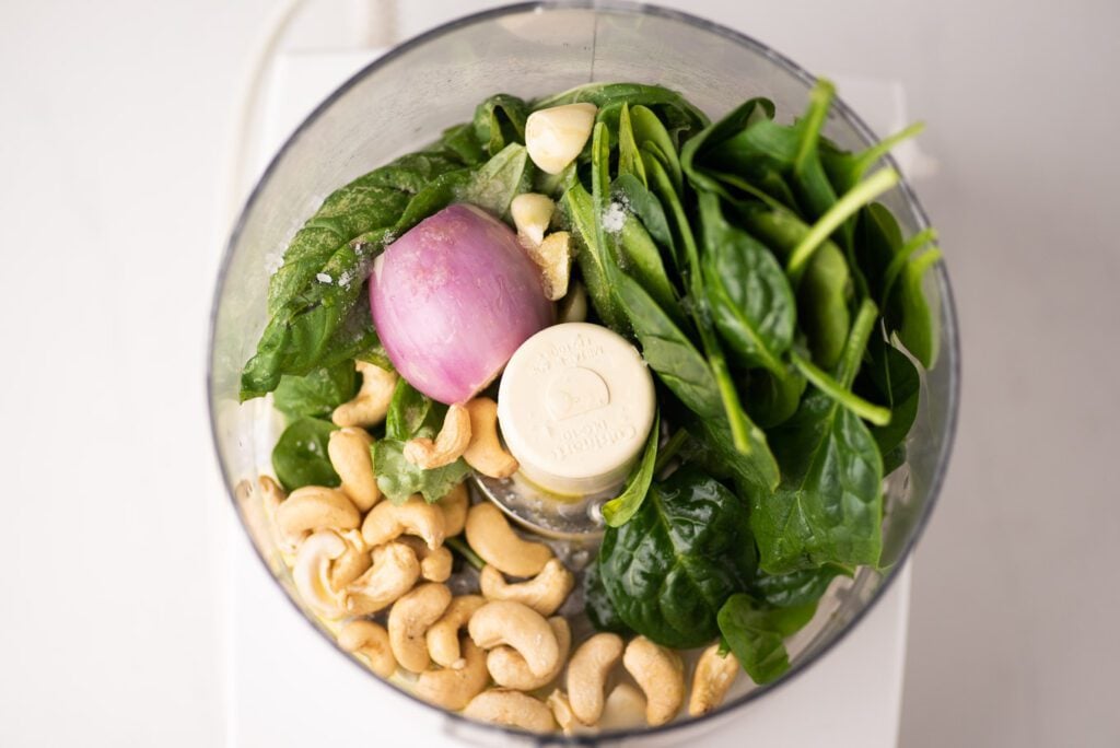 Food processor with basil, spinach, shallot, cashews, garlic, salt, olive oil