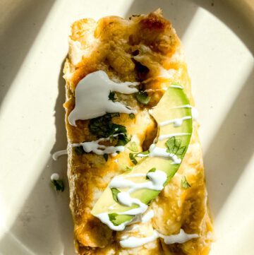 Enchiladas with green sauce, cream and avocado on a plate
