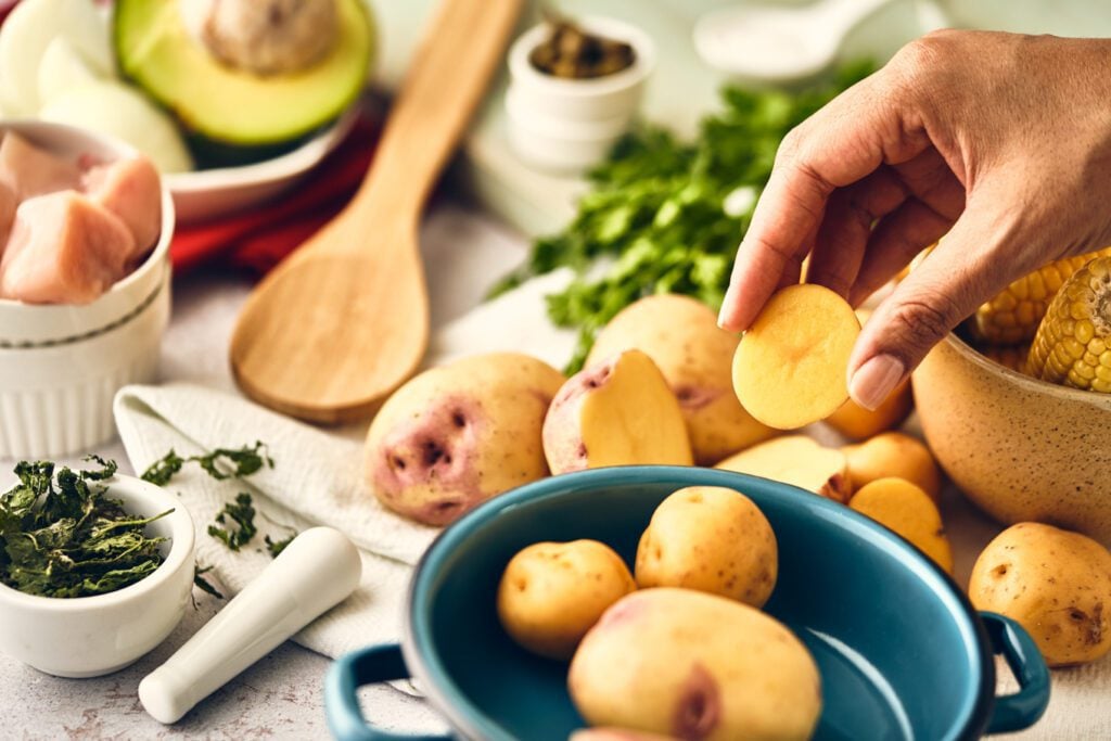 potatoes in a bowl, corn in a bowl, chicken in a bowl, wooden spoon, avocado, dried guasca in a bowl