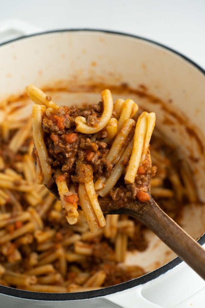 pot with pasta and sauce with wooden spoon