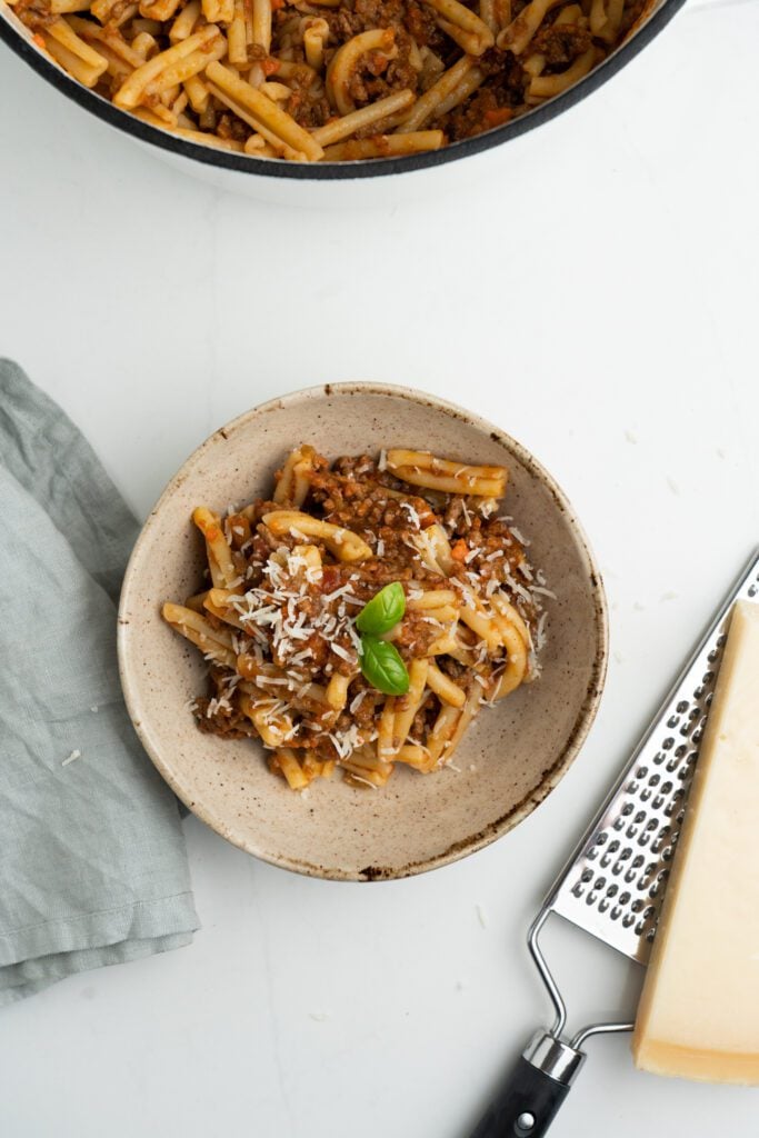 caserecce pasta on a bowl with parmesan cheese and basil. Grater with parmesan cheese and napkin