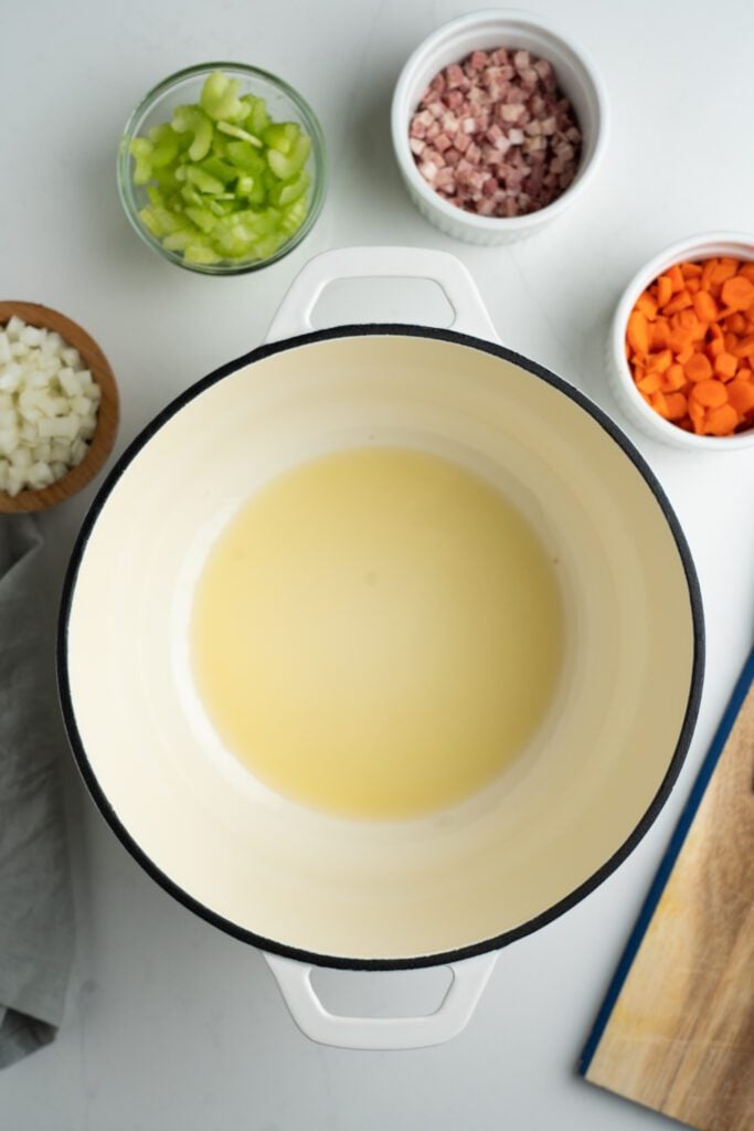 Stock pot with oil, pancetta, celery, carrots and onions in bowls