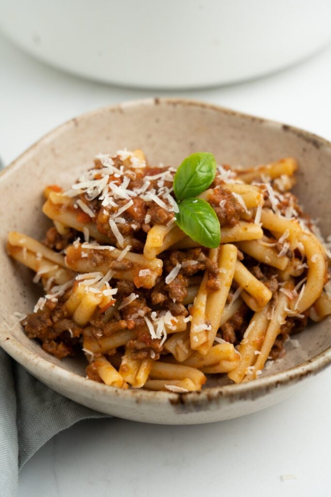 Casarecce with bolognese, basil and parmesan on a bowl