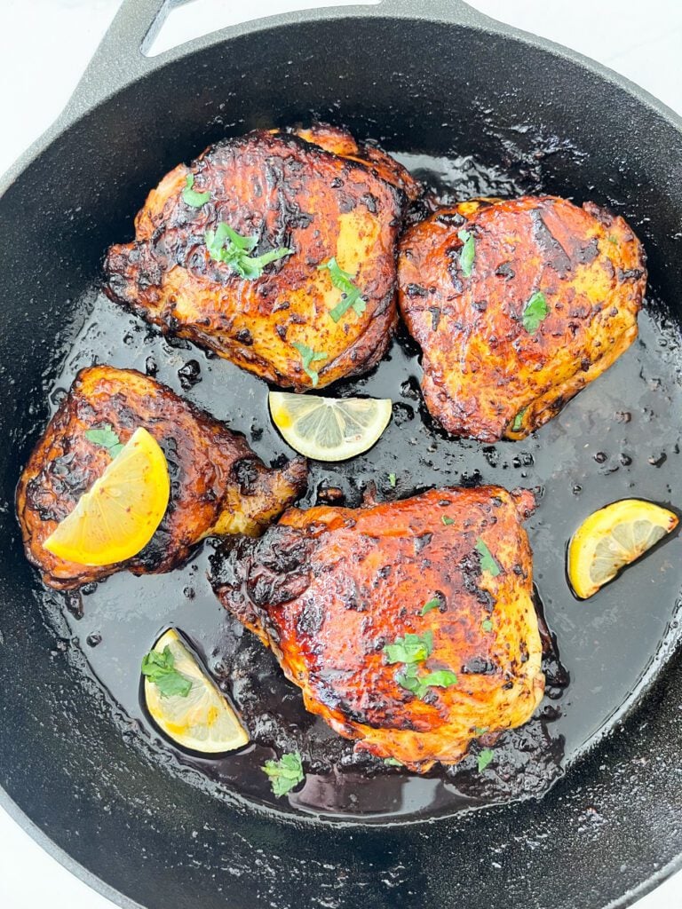 chicken thighs with lemon wedges on cast iron skillet