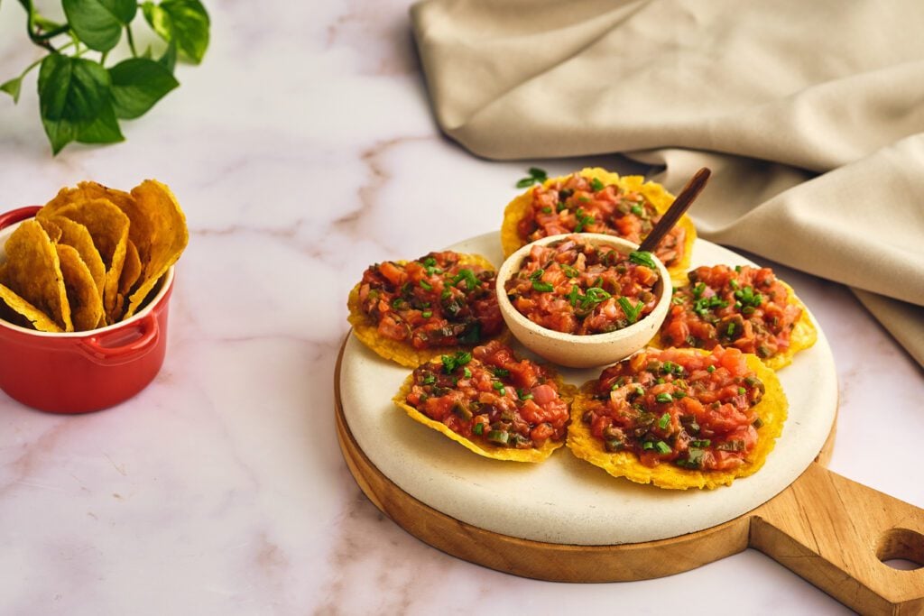 Hogao on a bowl with patacones on a wood board