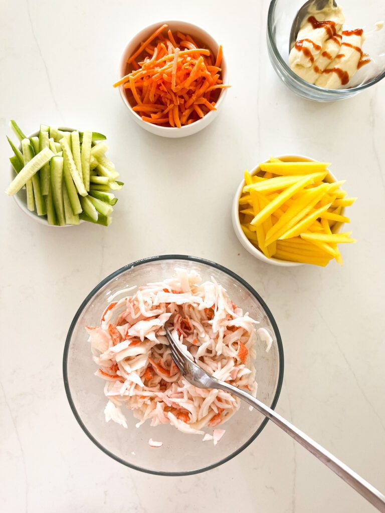 mango in a bowl, crab in a bowl, carrots in a bowl, cucumber in a bowl