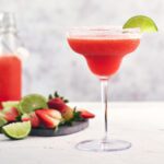 drink on a glass with ingredients to make drink in the background