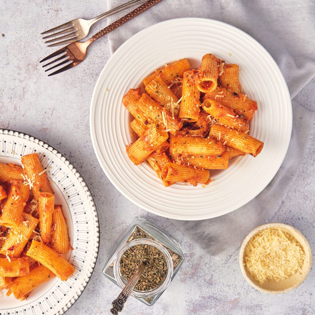 overhead view pasta plates with cheese and oregano for serving