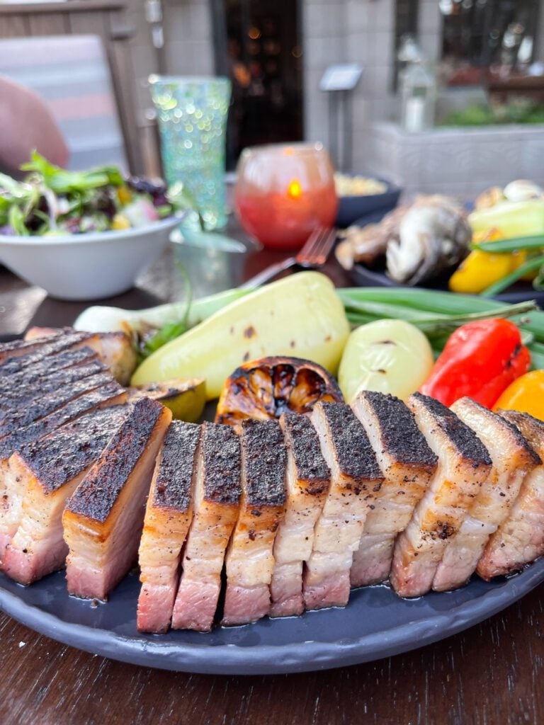 Pork belly on a plate with grilled veggies