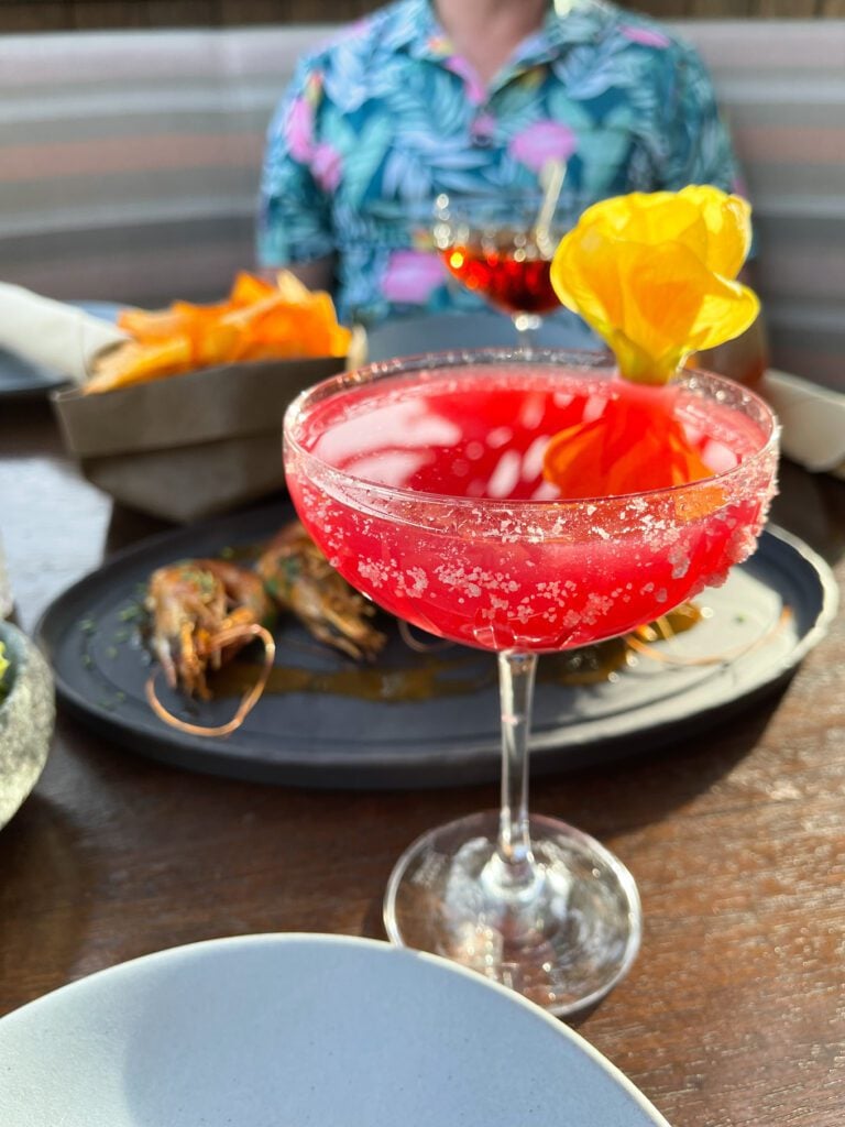 Prickly pear margarita with yellow flower on a dinner table setting