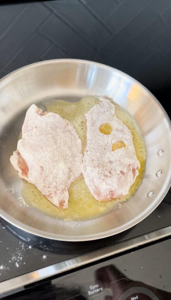 dredged chicken in a pan with oil