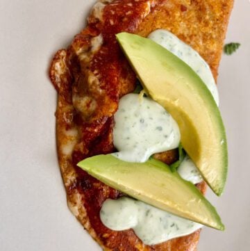 Tacos with cheese and crema topped with avocado.