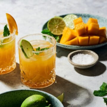 mango margarita on the rock with plate with cut up mango and pinch bowl with salt