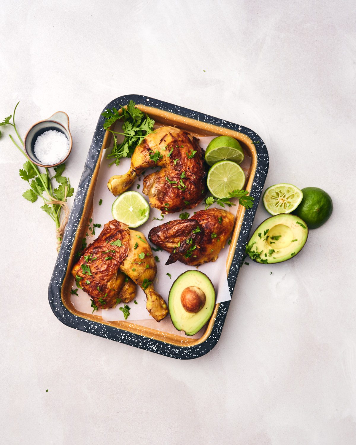 pollo asado with limes and avocado on a tray