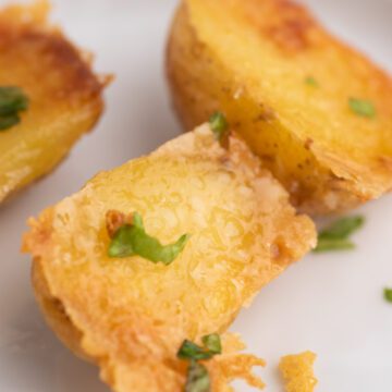 Parmesan crusted potatoes on white dish with parsley