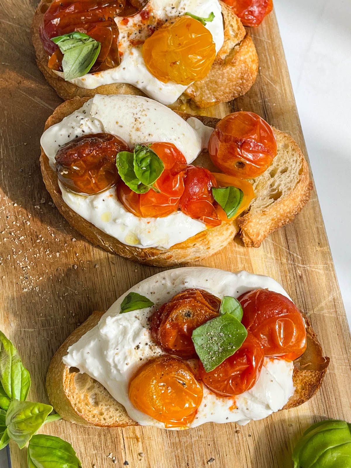 bread on wooden board with cheese, tomatoes and basil