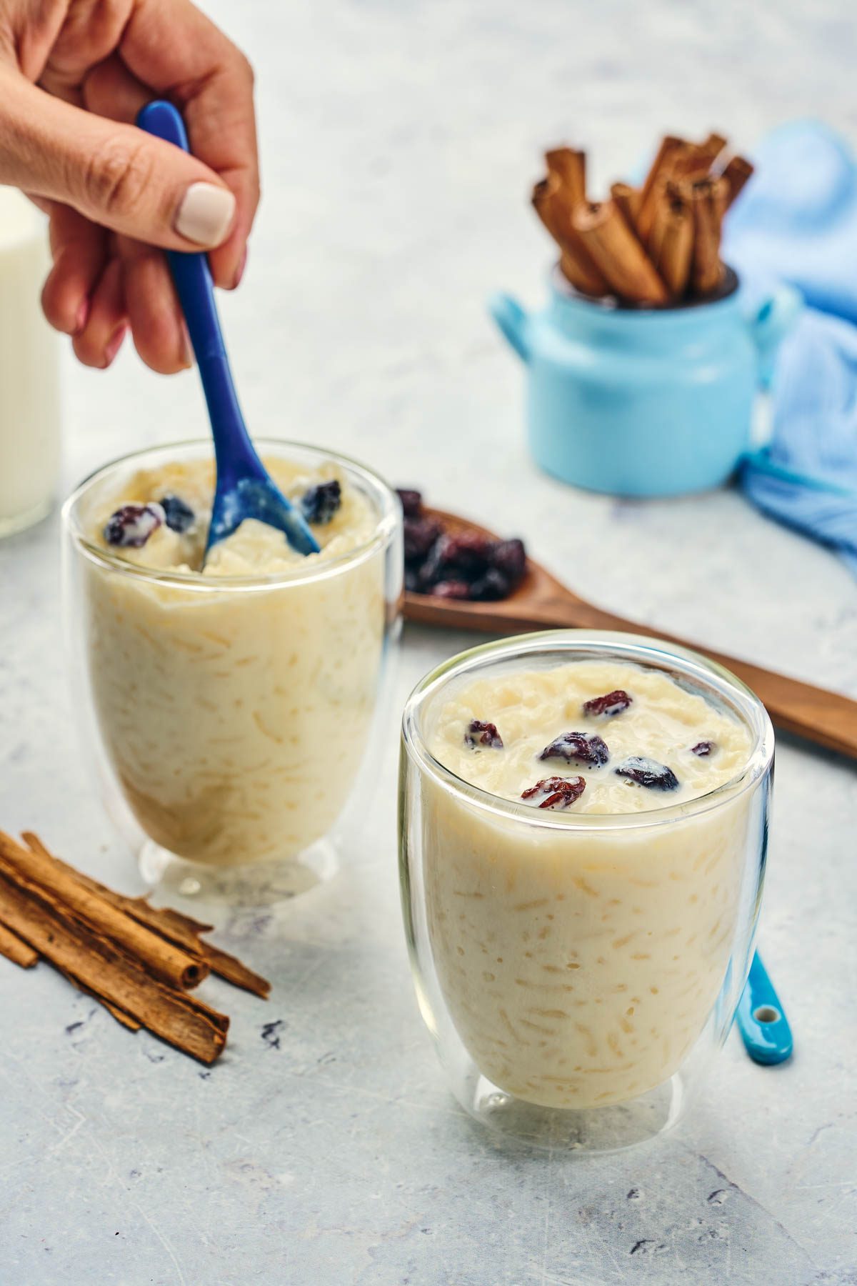 Arroz con leche in cups with blue spoons and cinnamon sticks