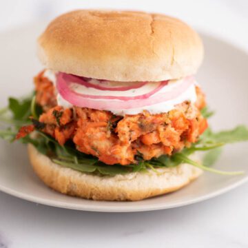 Salmon Patty with arugula, red onion and white sauce on a bun