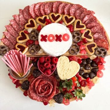 Cheese and meat board with heart shaped candy and cookies.