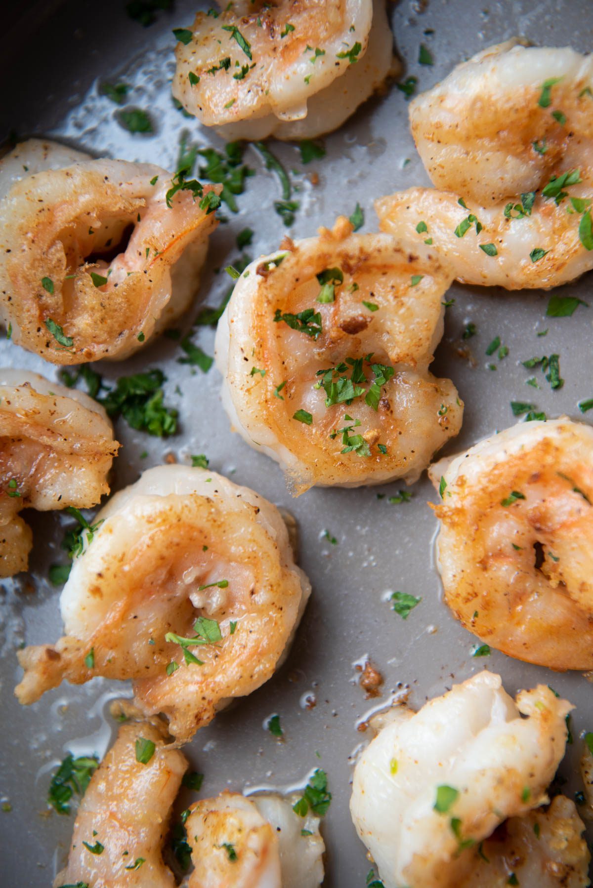 Shrimp in a pan with butter and parsley.