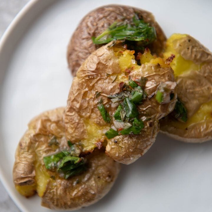 smashed potatoes on a plate with chimichurri
