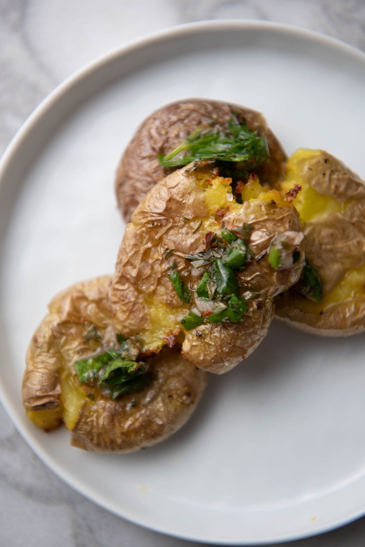 smashed potatoes on a plate with chimichurri