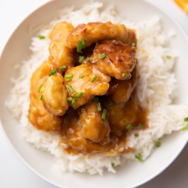 Orange chicken served over rice with chives.