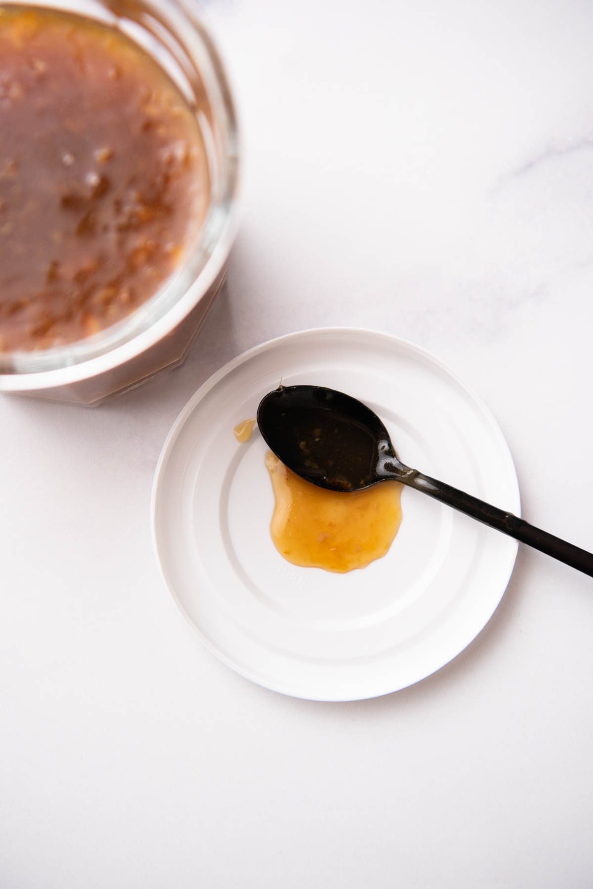 orange chicken sauce in a glass jar with a lid and spoon.