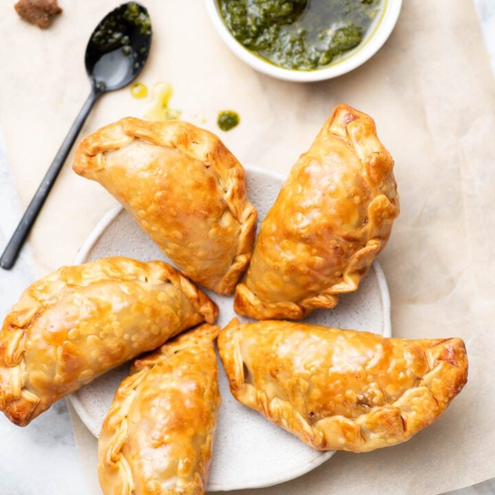 Argentinian empanadas on a plate with a side of chimichurri.