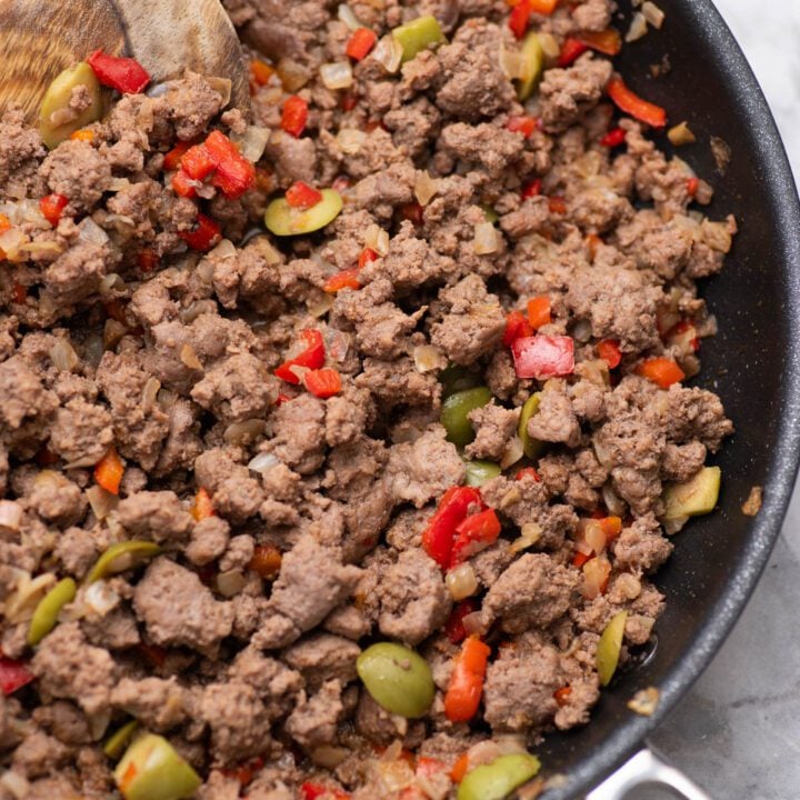 Picadillo in a skillet with ground beef, olives, onions and red peppers.